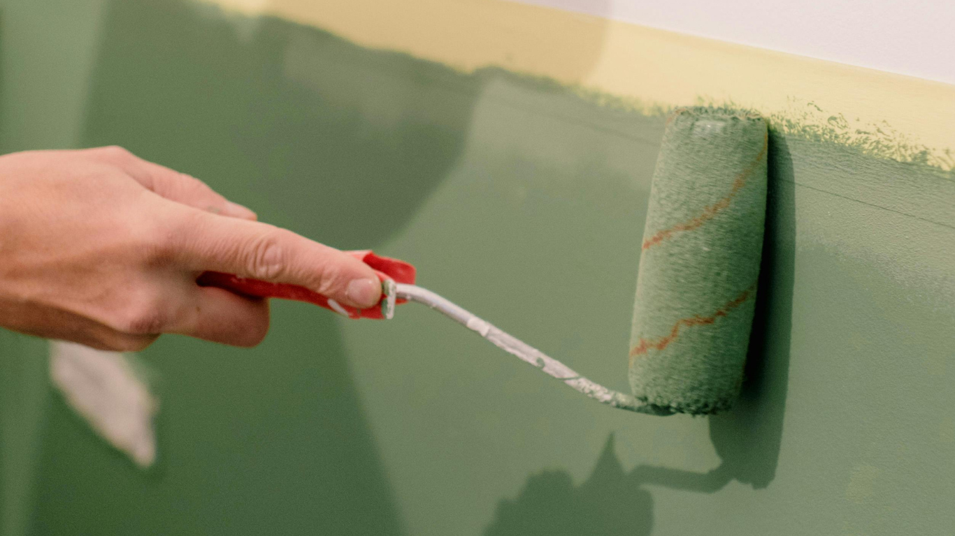 Applying green paint to a wall by professional painter from Elite Painting & Drywall