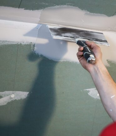 Worker applying drywall mud to ceiling, expert drywall services by Elite Painting & Drywall