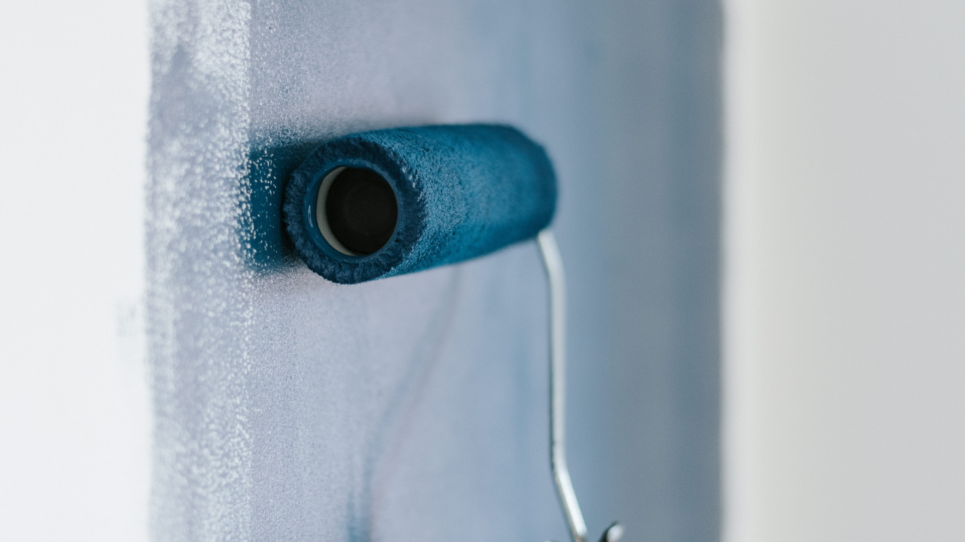 A paint roller applying a smooth finish on a wall during drywall installation services, highlighting professional painting services that support high-quality interior and exterior painting and preparation for durable exterior house painting results.